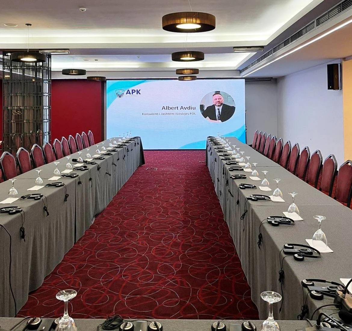 Conference room equipped with participant headsets and a large presentation display