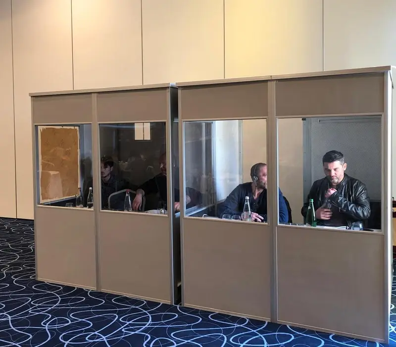 Professional interpreters working inside two enclosed conference interpretation booths