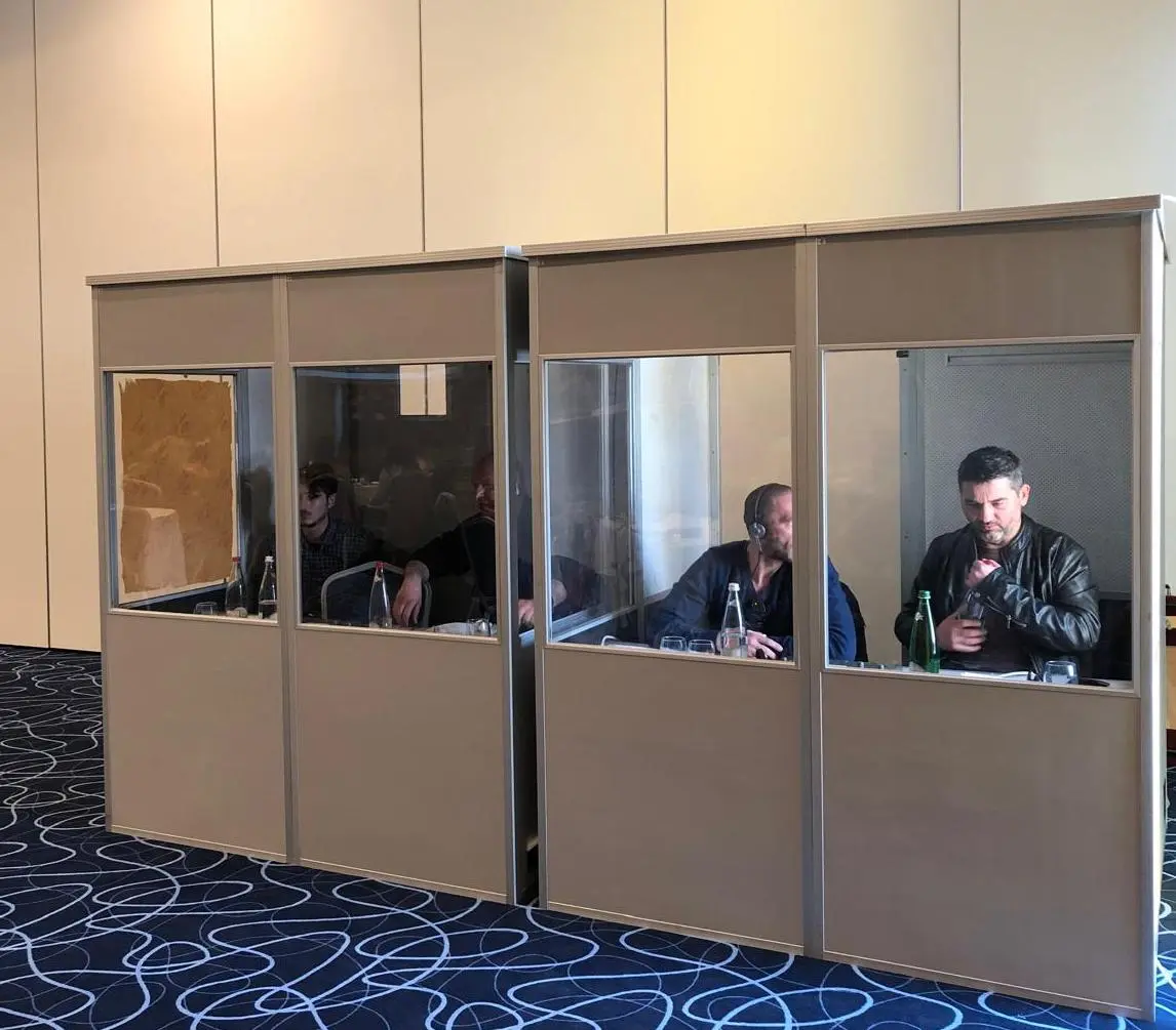 Professional interpreters working inside two enclosed conference interpretation booths